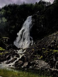 Scenic view of waterfall in forest against sky