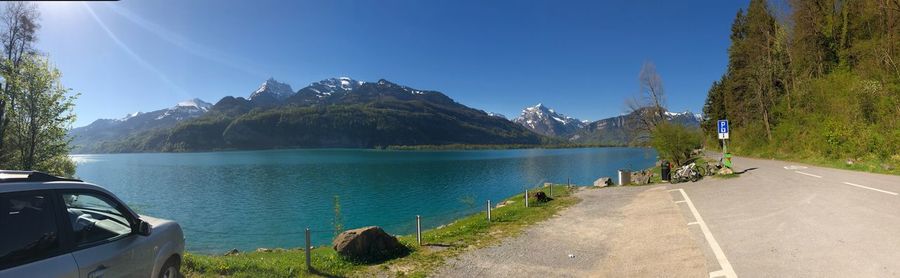 Panoramic view of road by mountains against blue sky