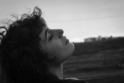 Portrait of young woman looking away against sky