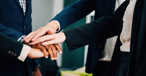 Midsection of business colleagues stacking hands