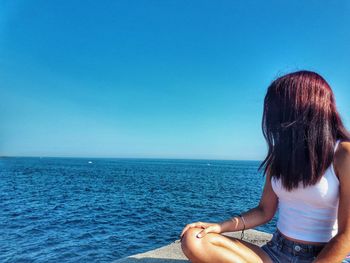 Rear view of woman looking at sea against clear blue sky