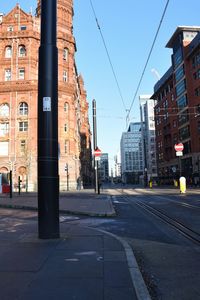 Road by buildings against sky in city