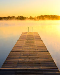 Pier over lake against sky during sunset