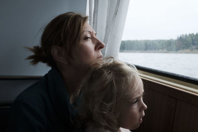 Portrait of woman looking away while sitting on window