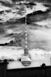 Communications tower and buildings against cloudy sky