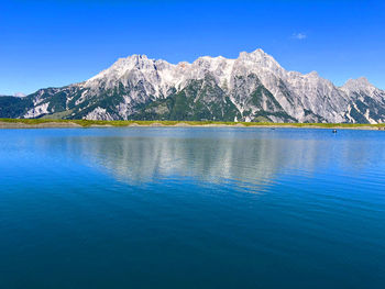 Scenic view of sea and mountains against clear blue sky