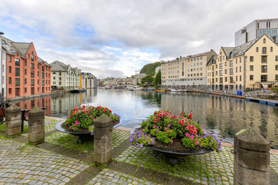 Buildings by river against sky in city
