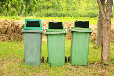 Garbage can on field against trees in forest