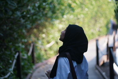Rear view of woman standing against blurred trees