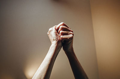 Cropped image of person holding hands against wall