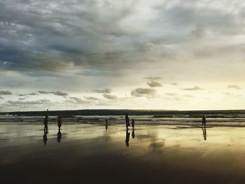 Silhouette people on beach against sky