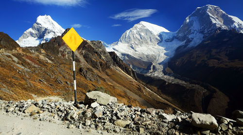 Sign post by stones with mountain peak in background