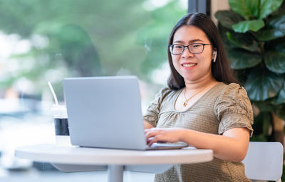 Young woman using mobile phone while sitting on table