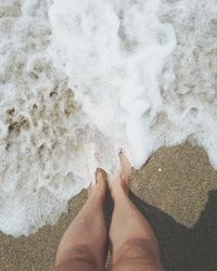 Low section of woman standing at sandy beach