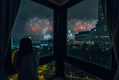 Woman looking at firework display during night