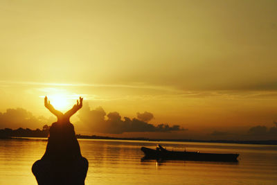 Silhouette person in sea against sky during sunset