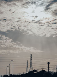 Low angle view of silhouette electricity pylon against sky during sunset