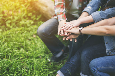 Midsection of couple holding hands sitting on grass