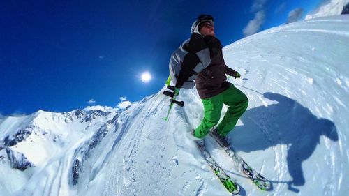 Man skiing on snowcapped mountain against sky