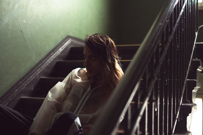 Woman looking away while sitting on staircase