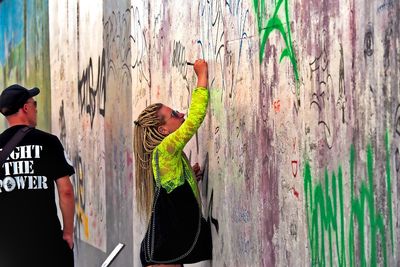 Rear view of people standing against graffiti wall