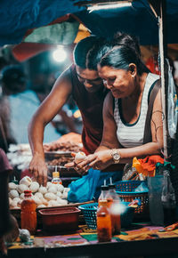 Woman with vegetables at market stall. 