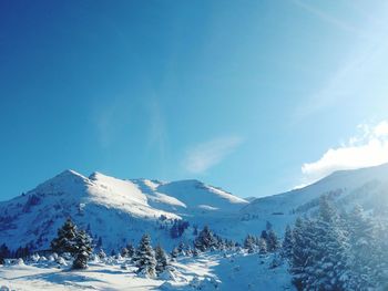 Low angle view of snowcapped mountains against blue sky