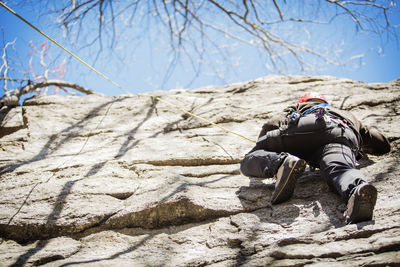 Low angle view of man climbing on rock