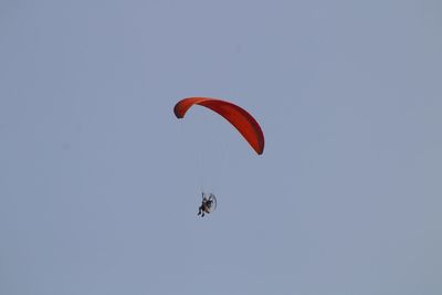 Low angle view of person paragliding against clear sky