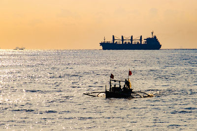 People on sea against sky during sunset