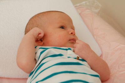 Close-up of baby girl relaxing on bed