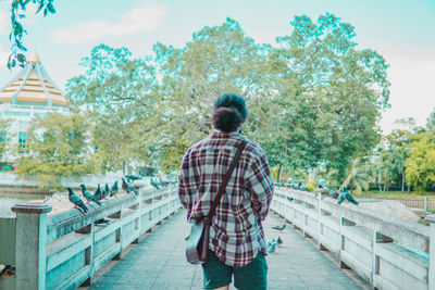 Rear view of man walking on footbridge