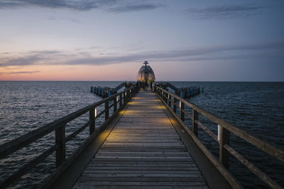 Pier over sea against sky during sunset