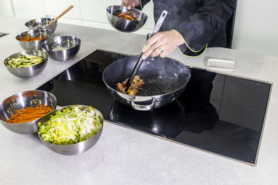 Midsection of person preparing food in kitchen at home