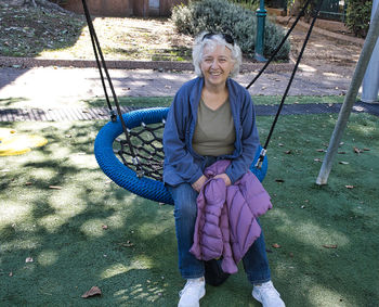 Smiling elderly woman on a swing in a good mood, positive attitude. person