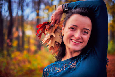 Portrait of smiling young woman with autumn leaves