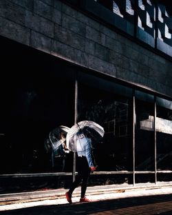 Woman with umbrella walking on street