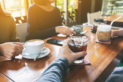 Midsection of couple holding coffee cup on table