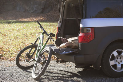 Man sleeping in car trunk by mountain bike