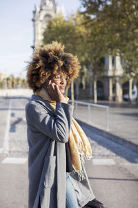 Woman talking on mobile phone while standing on city street