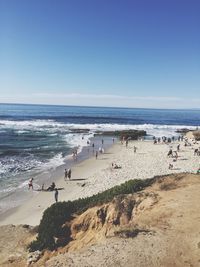 High angle view of people enjoying at beach against clear blue sky