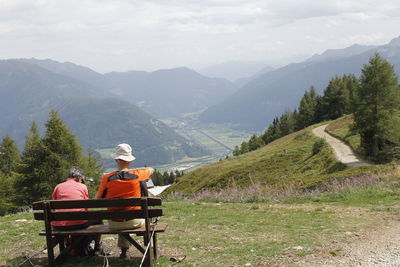 Rear view of people working on mountain against sky