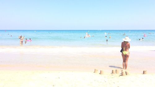 Rear view of people on beach against sky