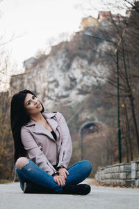 Full length of woman sitting on road