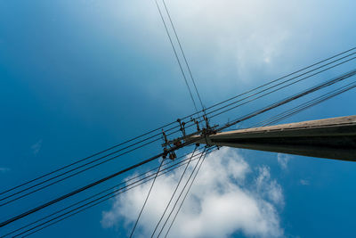 Low angle view of electricity pylon against blue sky