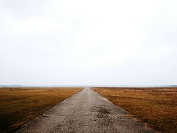 Empty road amidst landscape against clear sky