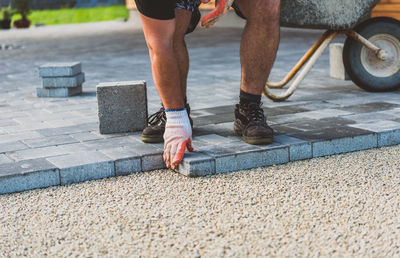 Construction worker arranging paving stones on street