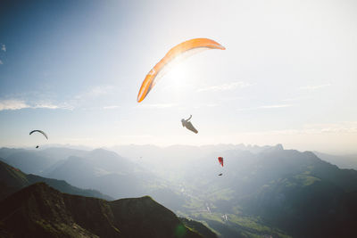 Man paragliding over mountains against sky