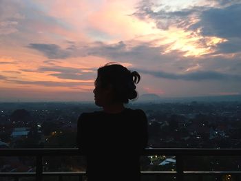 Silhouette of man in city against sky during sunset