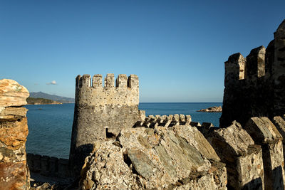 Stone fort  wall by sea against clear blue sky
